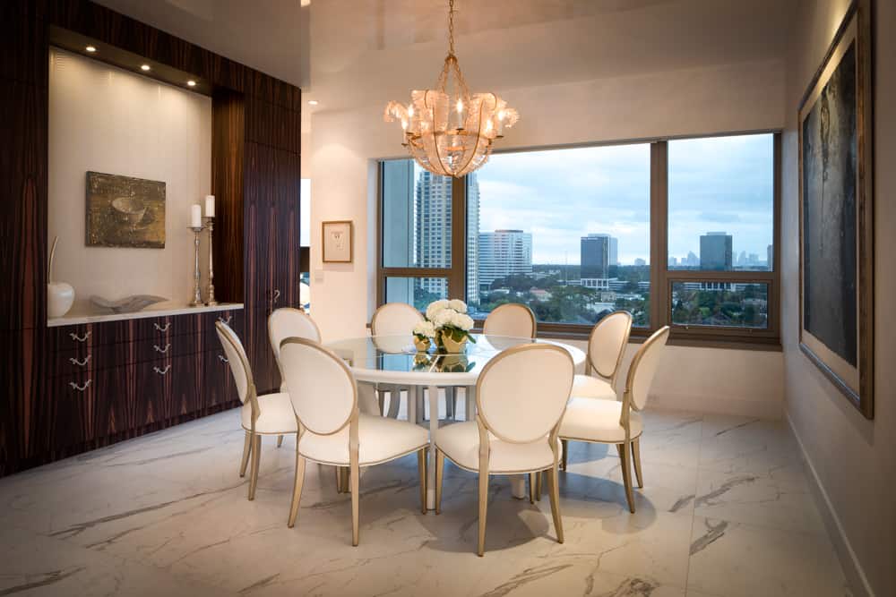 custom dining room buffet flanked by floor-to-ceiling storage cabinets in makassar veneer set off by white upholstered chairs and luxuriously detailed dining room table all designed by eggersmann