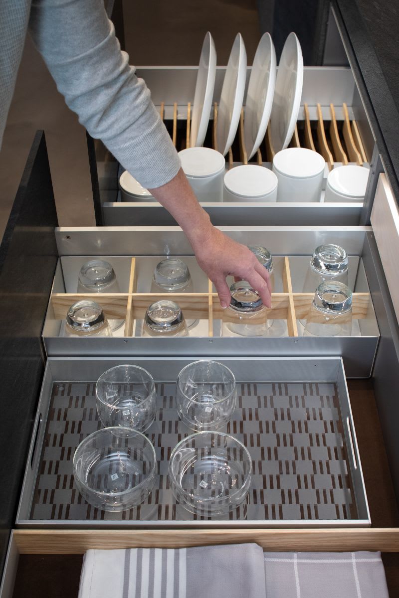 woman selecting a glass from an eggersmann drawer in which a variety of boxtec drawer organizing accessories are installed