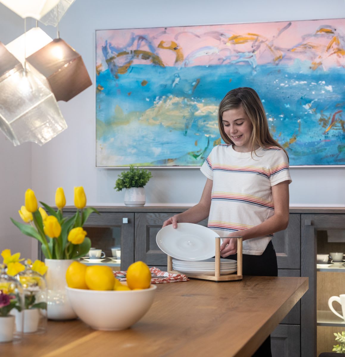 girl sets the table with plates from a boxtec plate caddy that protects plates from sliding while in the drawer and conveniently totes the plates to the table for easy setting