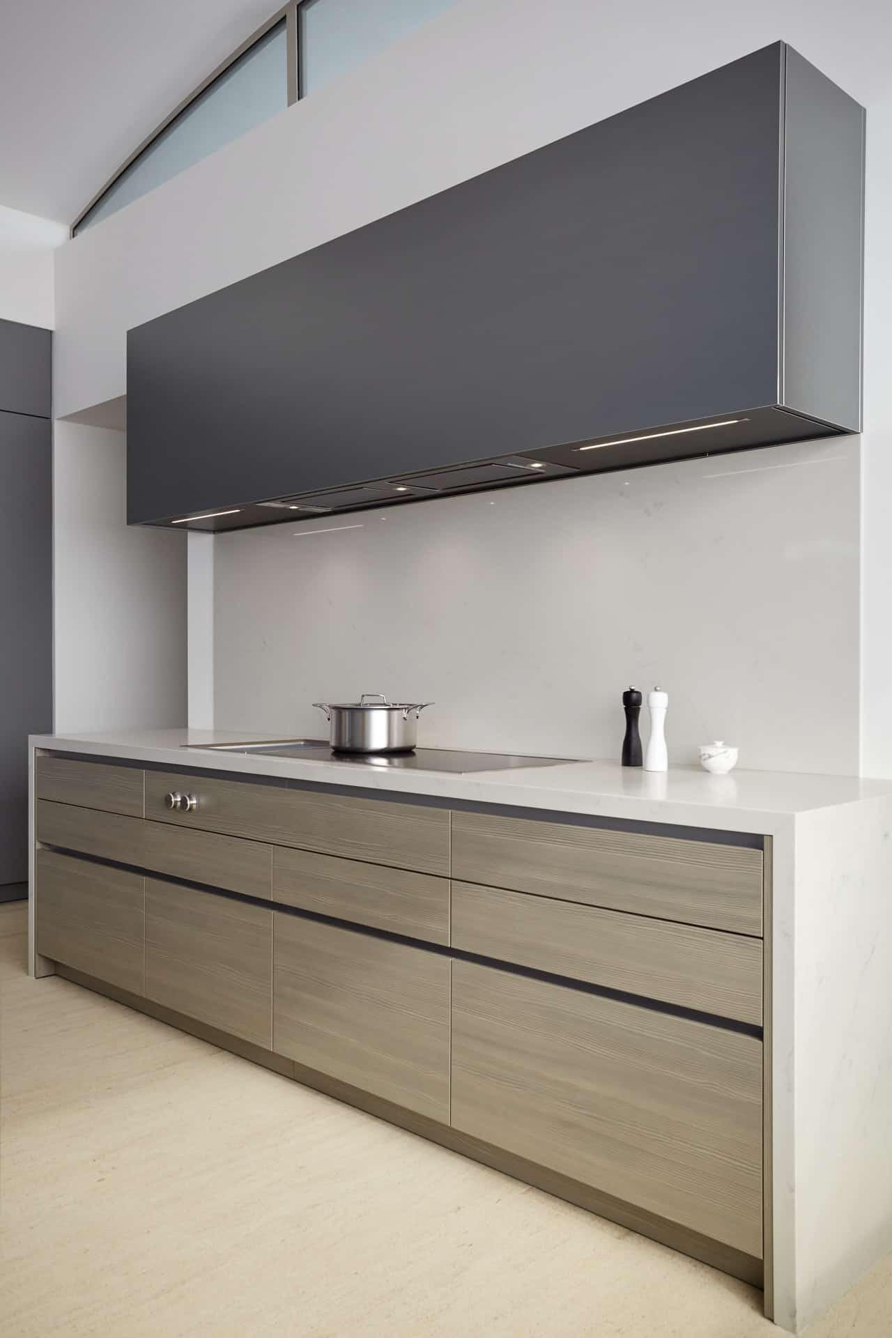Main kitchen's induction stove and beautifully paired cabinetry finishes in woodgrain laminate and dark aluminum