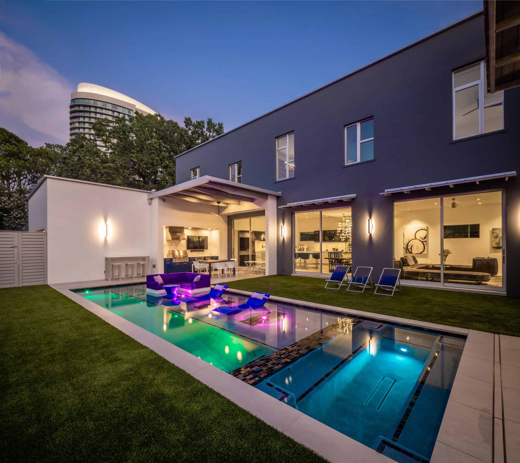 ultra modern pool lit at dusk behind a newly built home in upper kirby