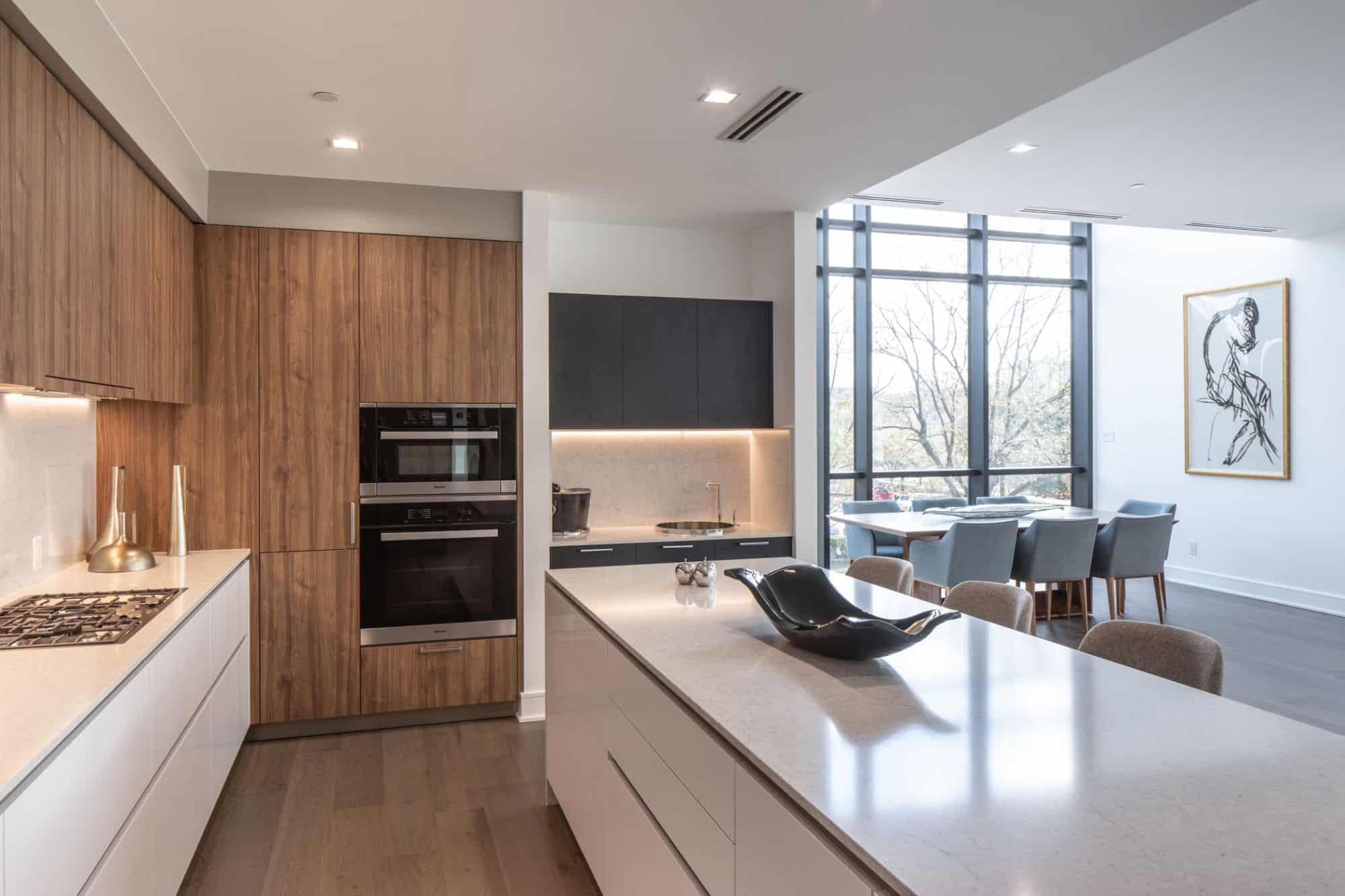 Luxury solid surface kitchen with natural light wood accents amplifies the natural light from the floor to ceiling windows