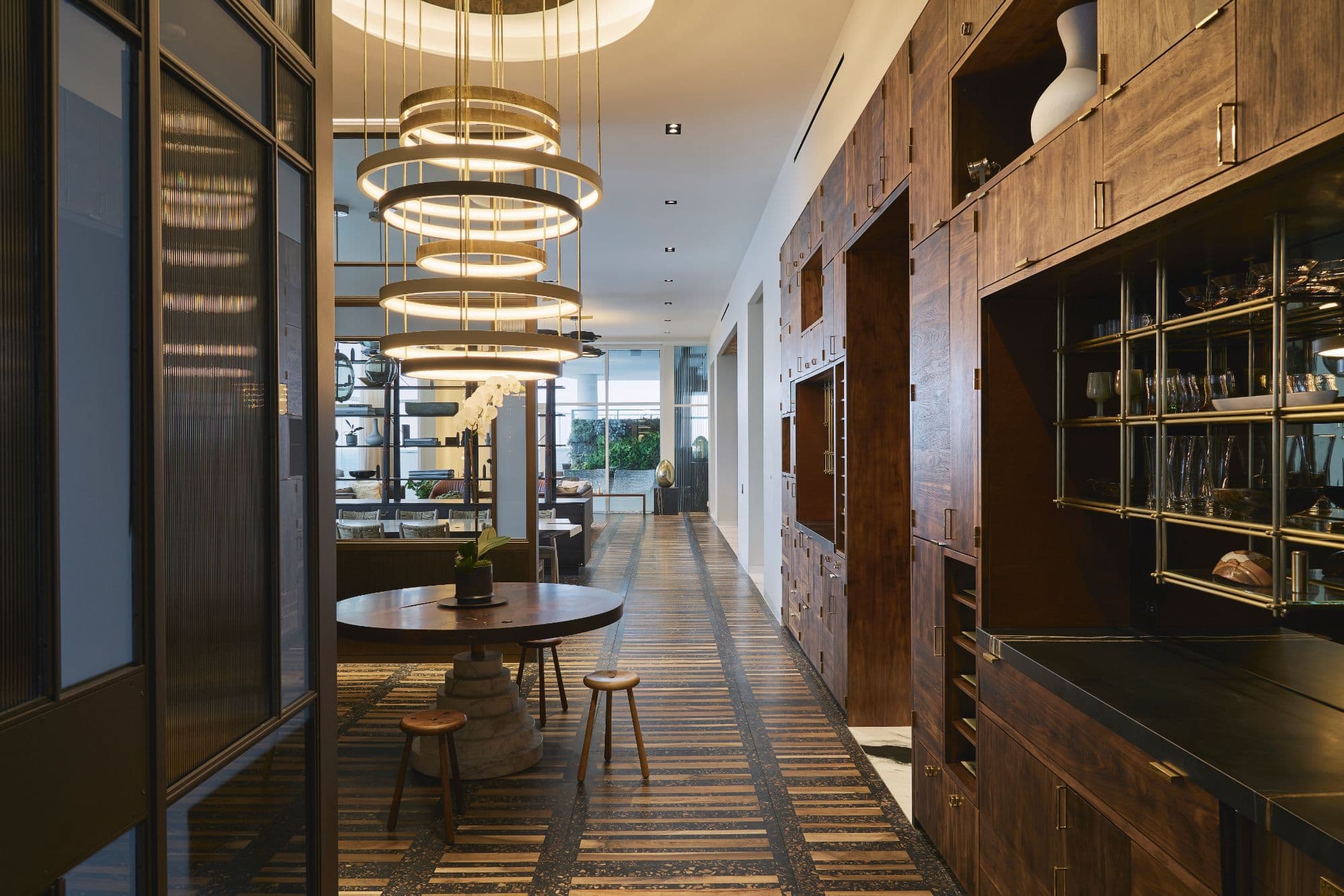 bistro dining area with unique modern chandelier outside a decadent hallway full of storage area inside a penthouse of the arabella luxury high rise in houston