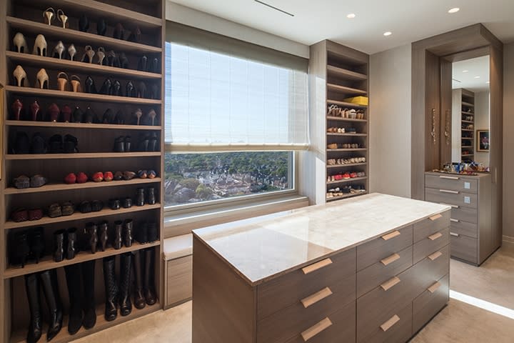 storage galore with island and custom shelving in a Schmalenbach closet for her