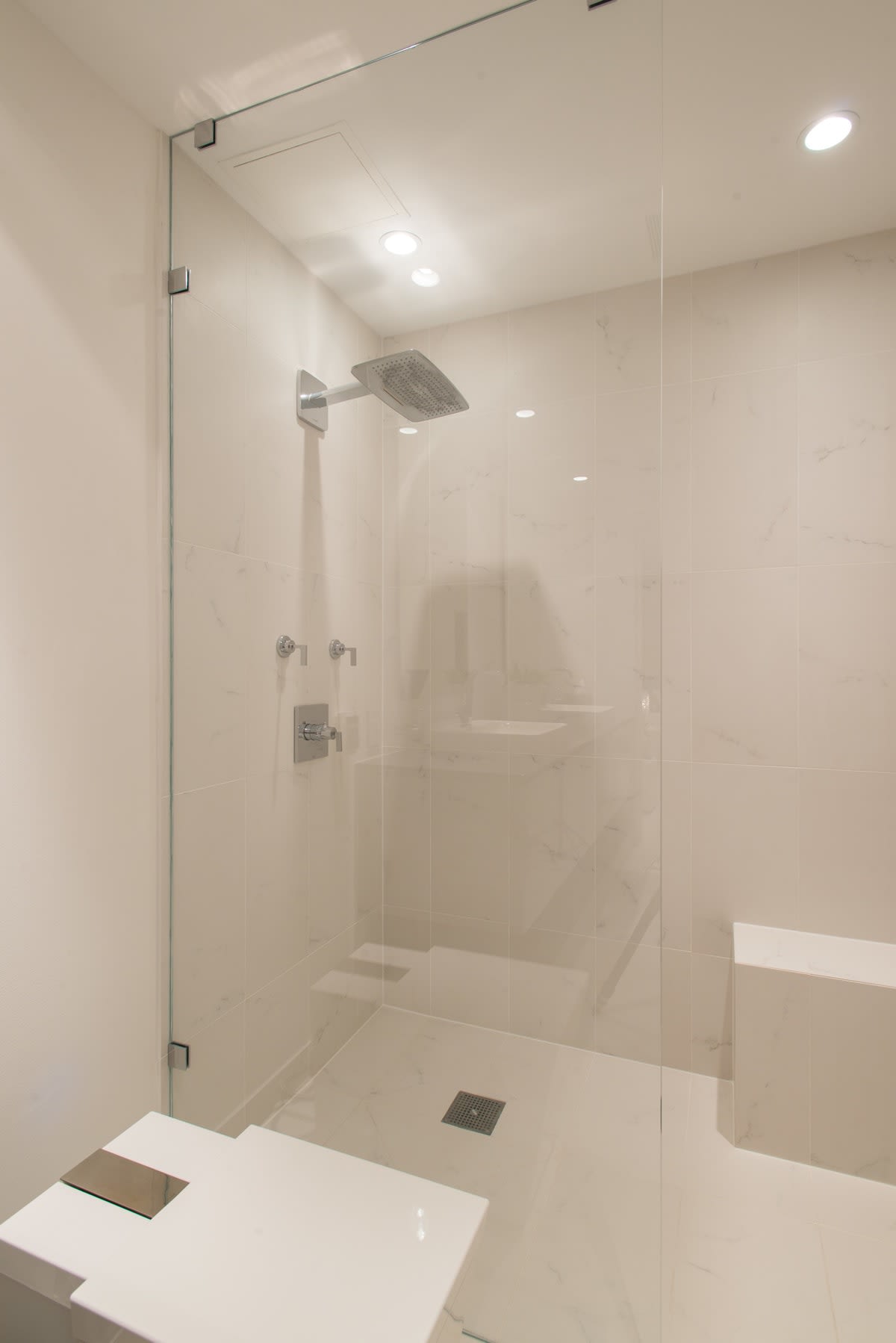 whilte marble shower with glass wall keeps the space clean and airy