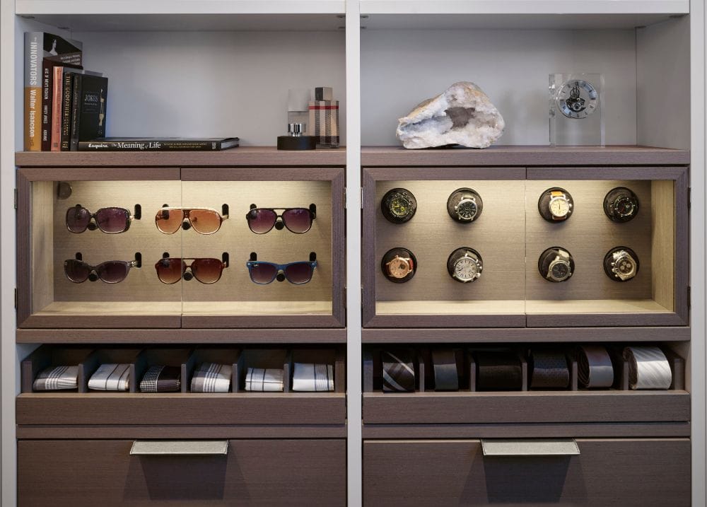 led lighting highlights a luxury closet owner's collection of sunglasses and watches in custom display cabinets