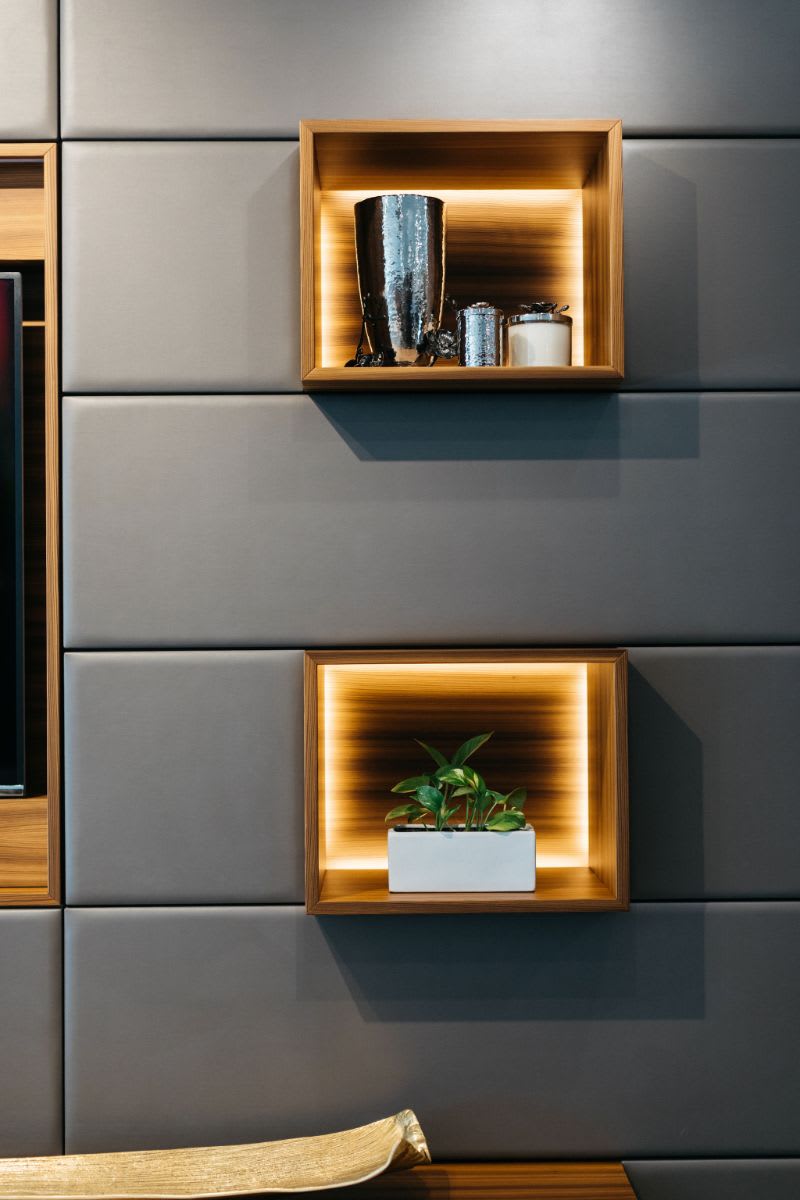wood cubes on an upholstered media wall with LED backlighting to highlight items on display
