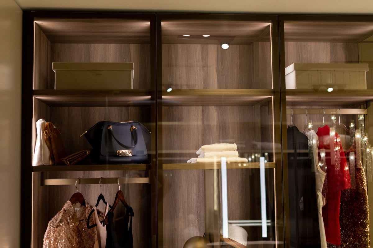 led lighting used inside glass front cabinetry in a luxury walk-in wardrob highlights favorite fashion items