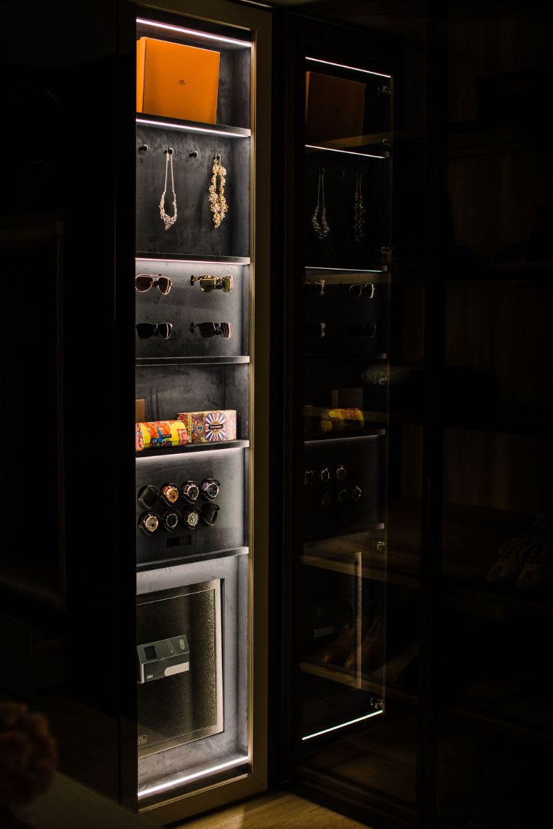 led lighting dramatically highlights cherished jewelry, watches, and other possessions as well as offers a nightlight in this walk-in wardrobe