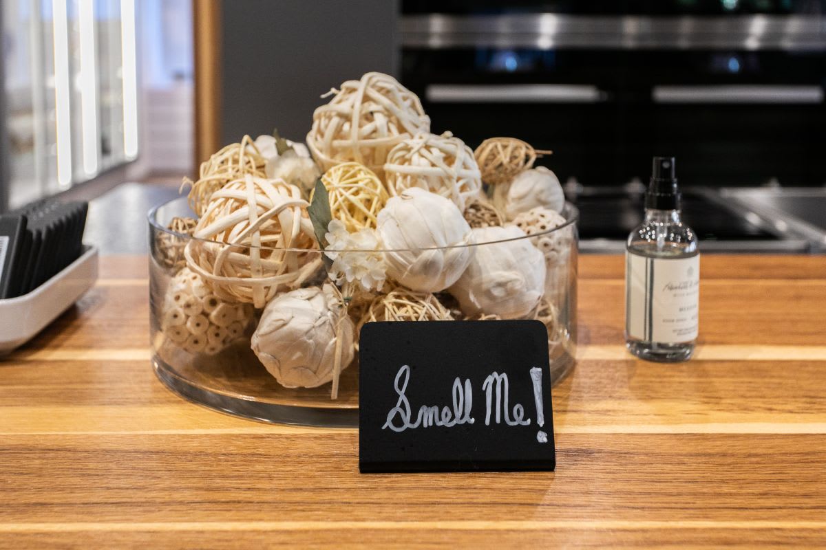 sign saying "smell me" inviting guests to smell the zest of a bowl of ball made from strips of smoked wood