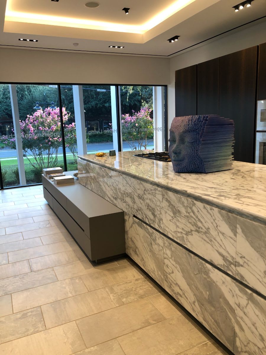 a face sculpture by gil bruvel sitting on a kitchen display island in the eggersmann dallas showroom as part of part of patron magazine's curated 2021 art exhibition and dallas design district showroom tour