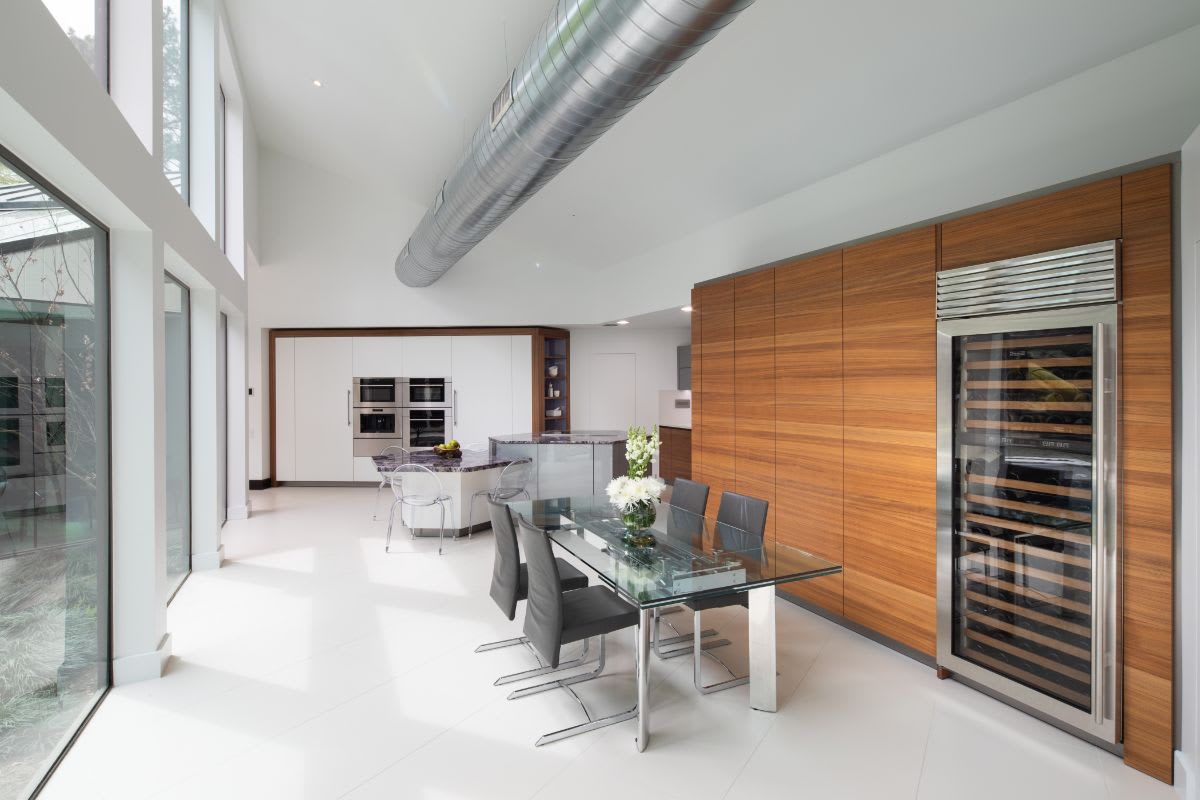 very peri kitchen and dining area designed by eggersmann features a horizontal walnut cabinet wall in the dining room with white and grey cabinets in the kitchen that set a backdrop for the very peri countertop