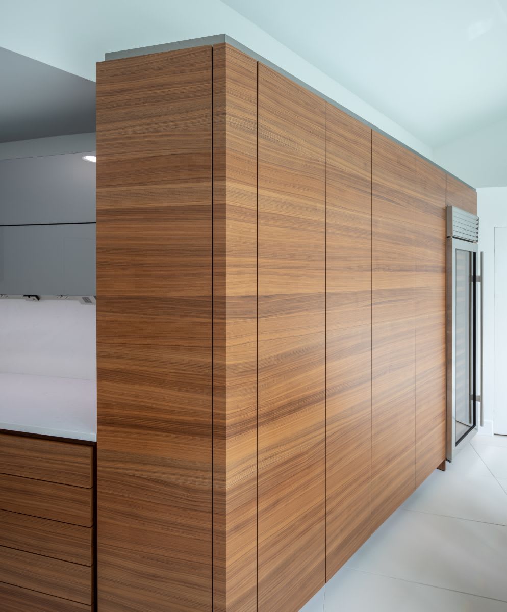 eggersmann designed horizontal-grained walnut cabinet wall featuring a hideaway bar area behind pocket doors that are closed and looking very minimal