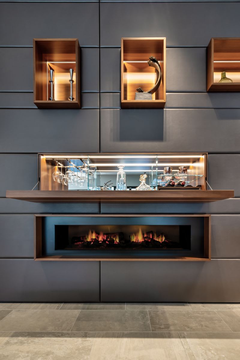 modern horizontal dimplex fireplace in an eggersmann-designed media wall below an opened hidden bar