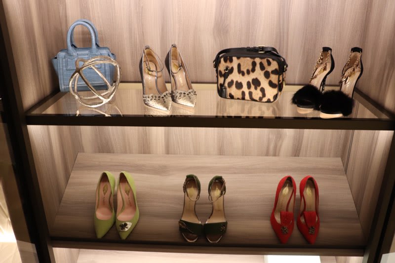 nadia catini shoes and purses displayed in the la showrrom's luxury wardrobe on a backlit shelf with wood veneer backing