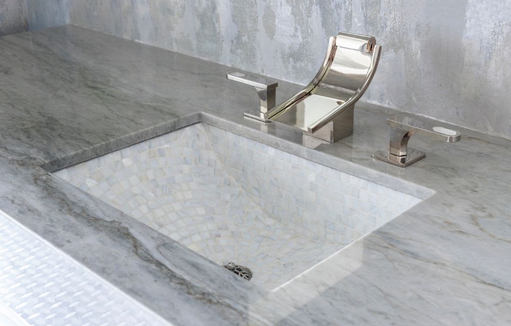 unique waterfall faucet on a formal powder room vanity in a belfiore residence