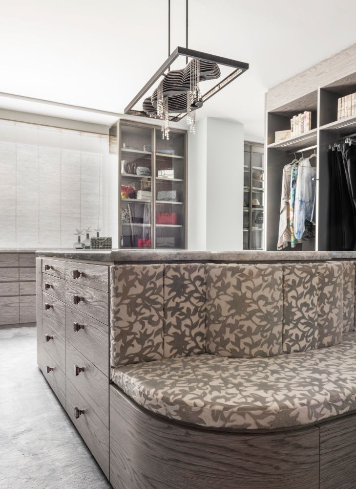 Luxury closet island with built-in upholstered bench designed for homeowners of a belfiore residence in houstoncollection