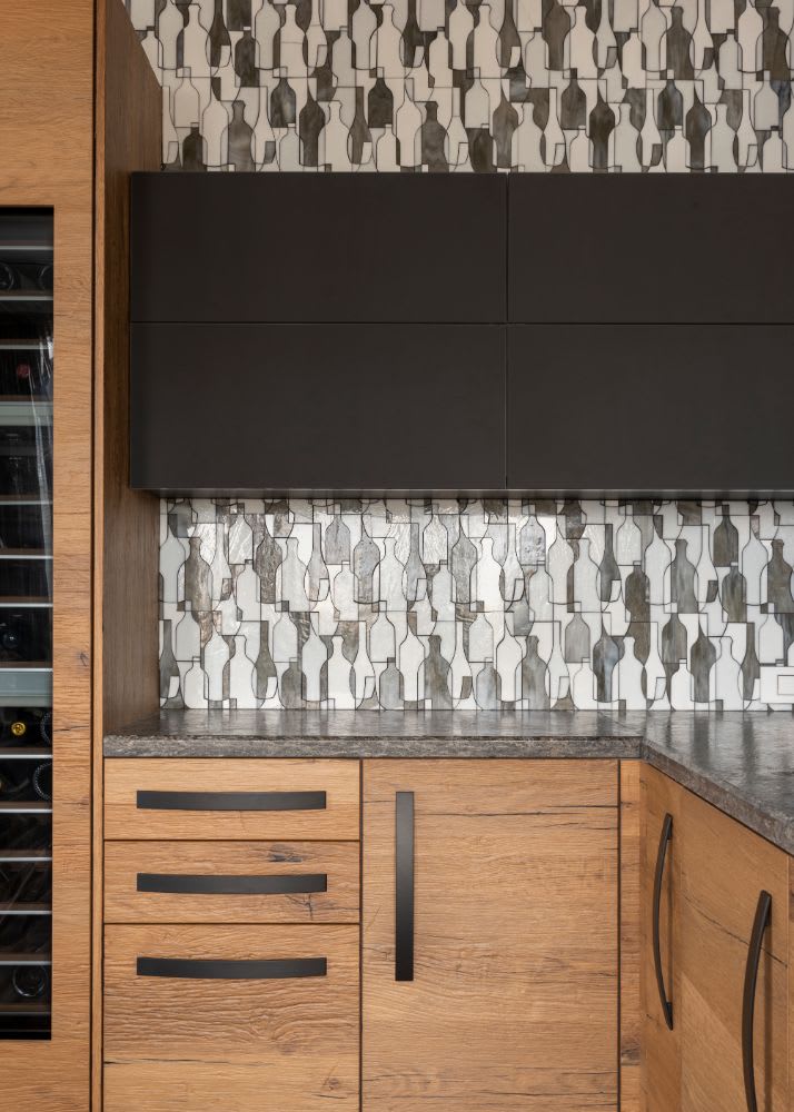 tile backsplash with a wine bottle motif in a wine bar designed for a belfiore houston residence