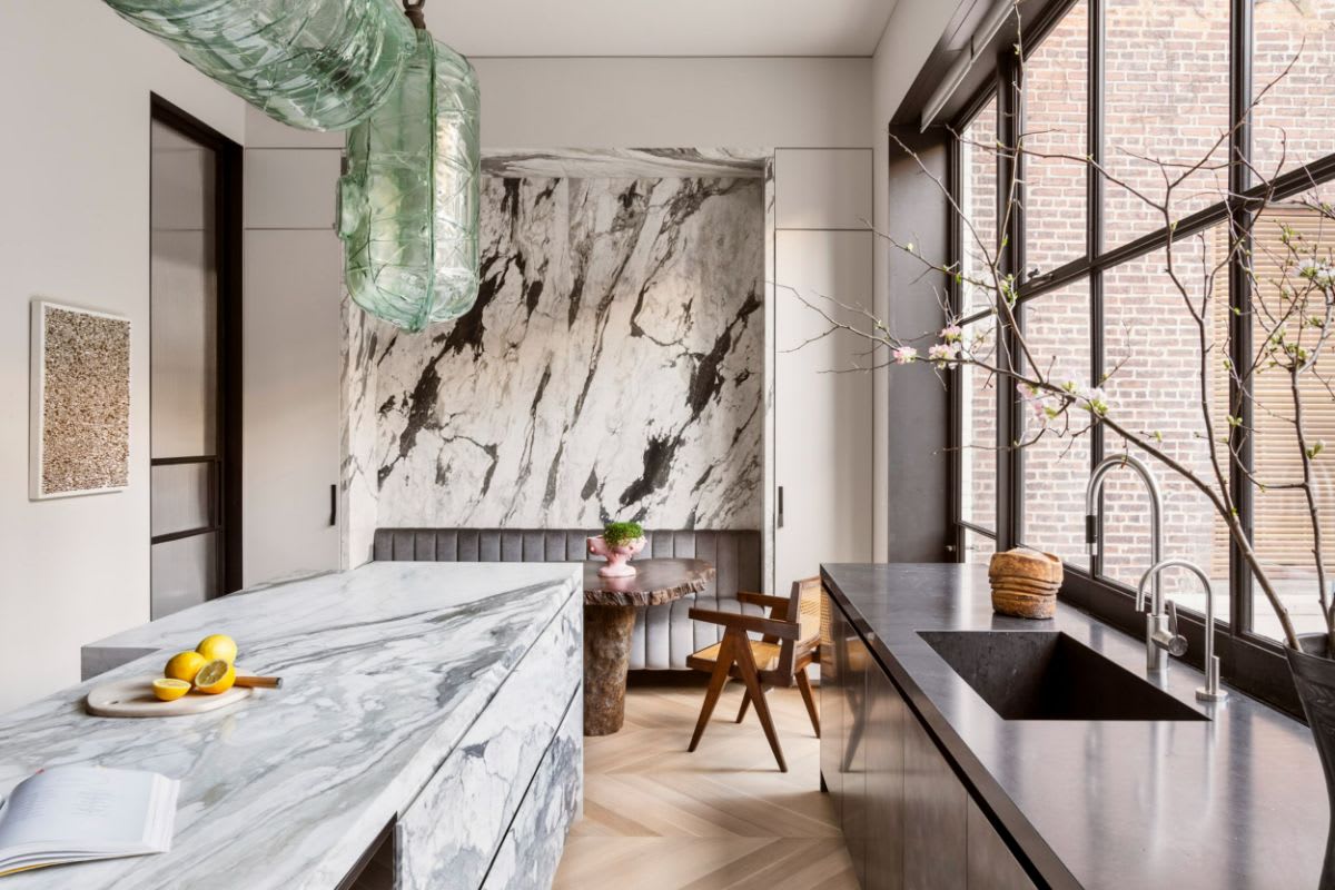 eggersmann-designed stone island and marble clad wall accent behind an upholstered banquette dining area