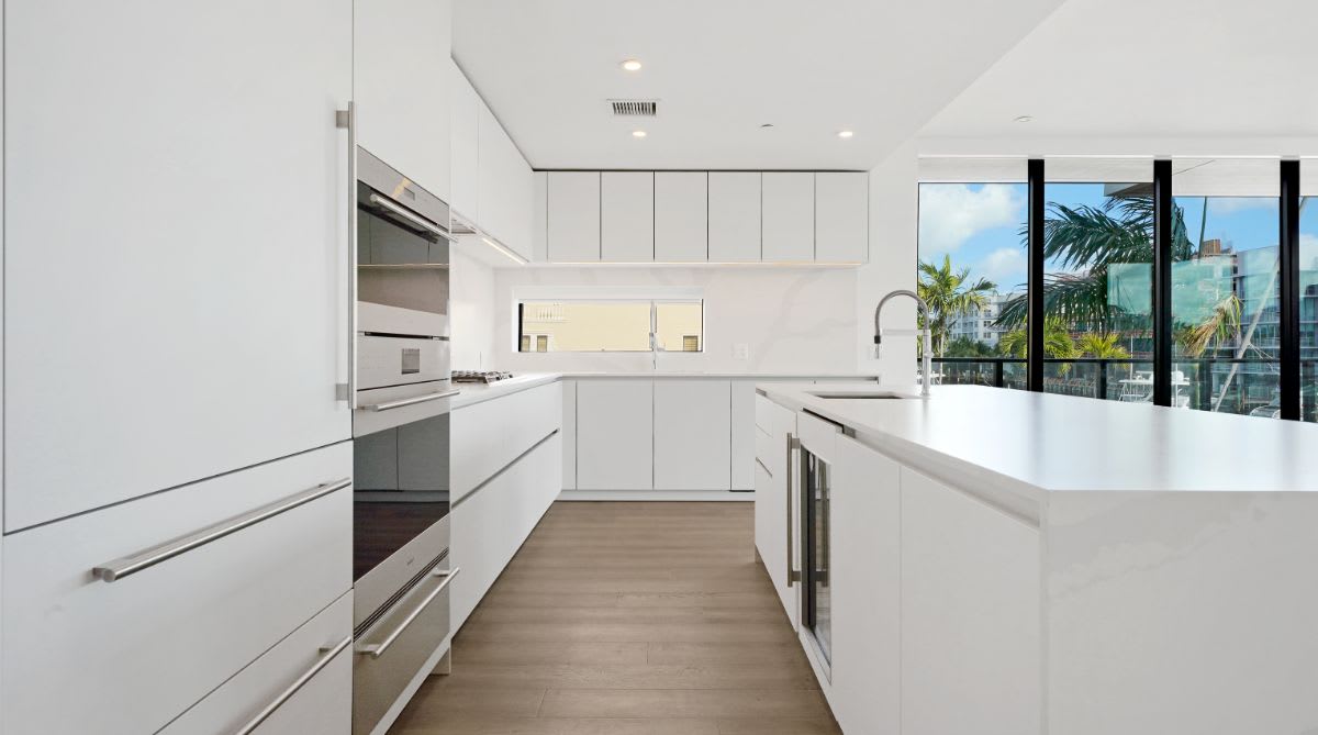 galley of an all-white kitchen designed by eggersmann for a one24 residences penthouse in fort lauderdale florida