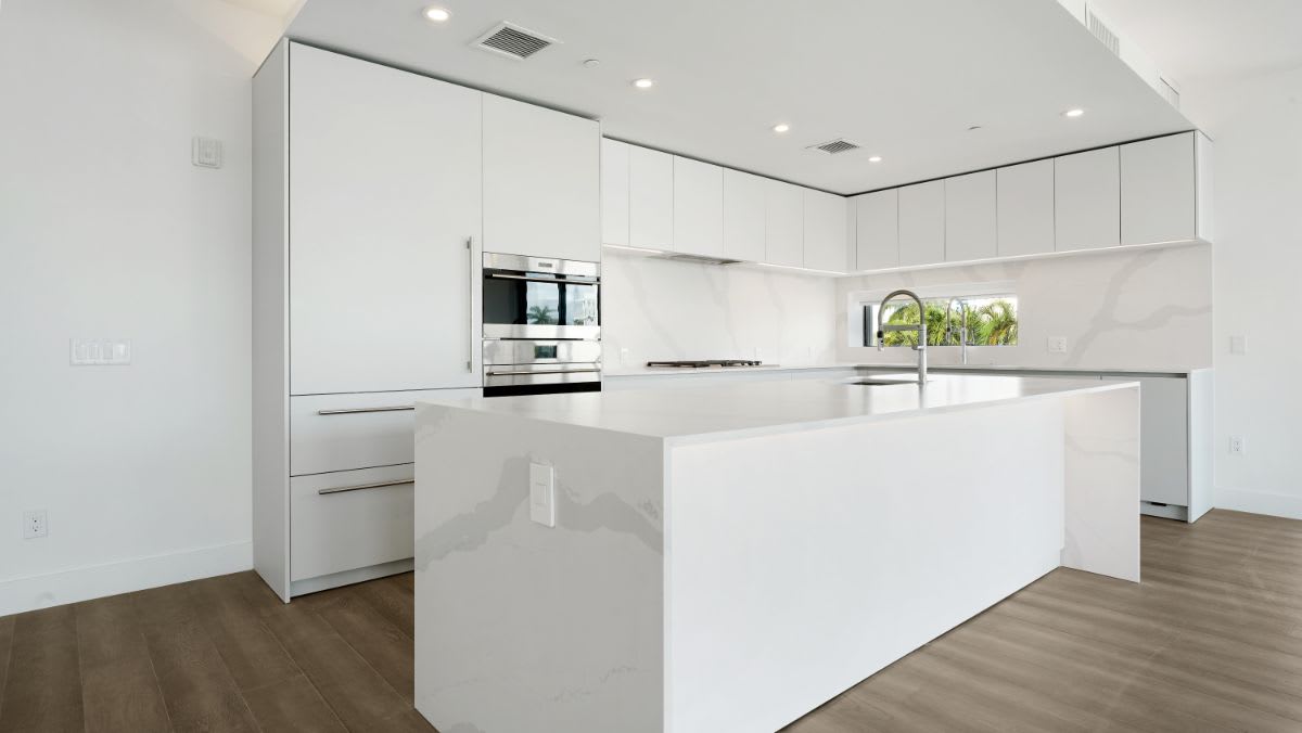 all-white kitchen with high-end appliances designed by eggersmann for a one24 residences penthouse in fort lauderdale florida