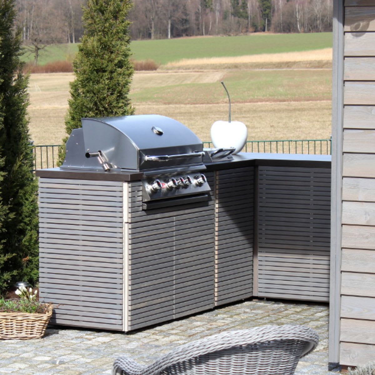 outdoor kitchen with horizontal slatted cabinet fronts in gray with built-in luxury grill