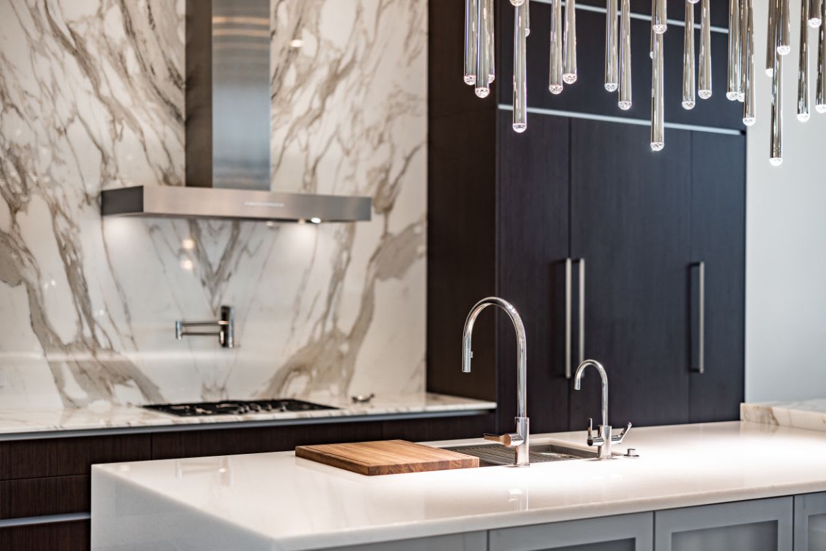 closeup of woodfield country club boca raton kitchen's miele stove top and stainless hood with the galley workstation sink