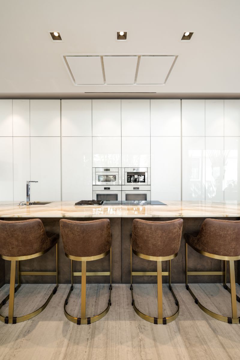 breakfast bar in front of the floor-to-ceiling appliance wall cabinetry in an eggersmann kitchen of a miami beach intracoastal luxury home