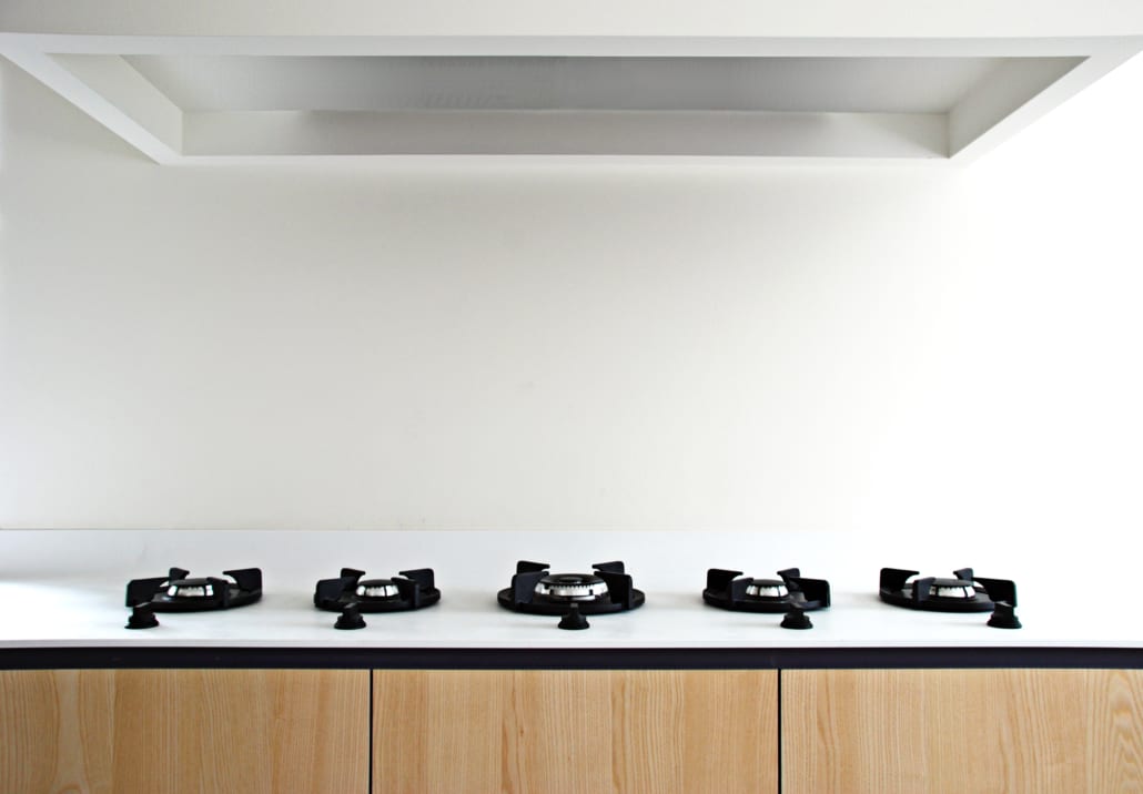 closeup of pitt cooking integrated gas burners in a wood-grain island with white countertop