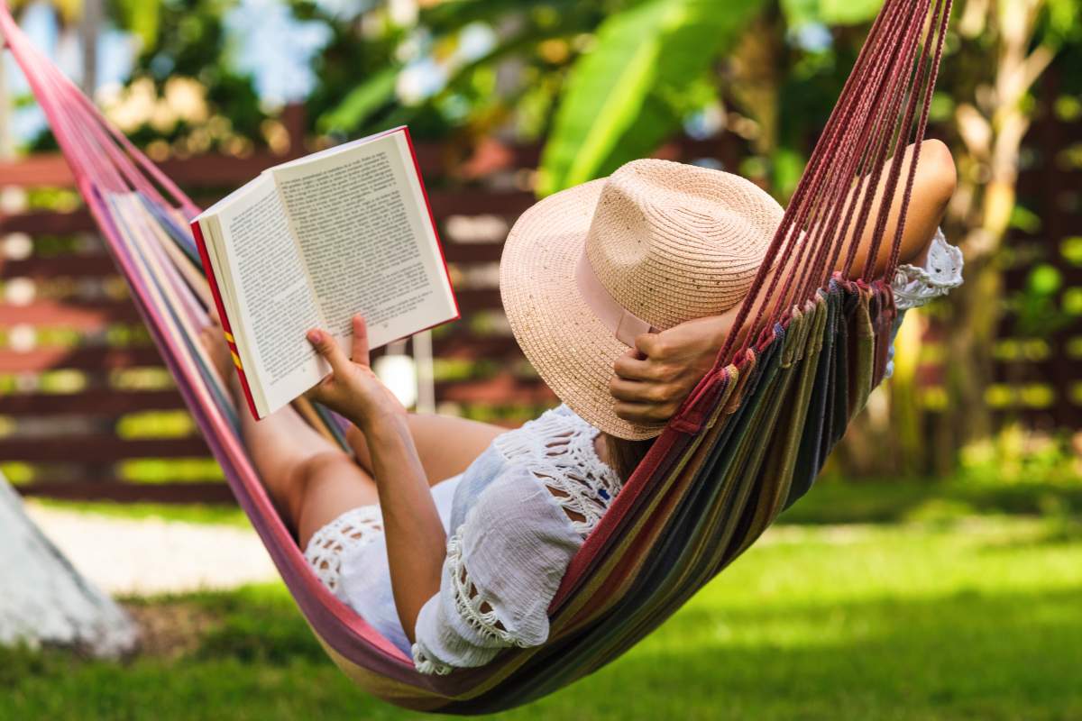 woman lazily reading a book in a hammock