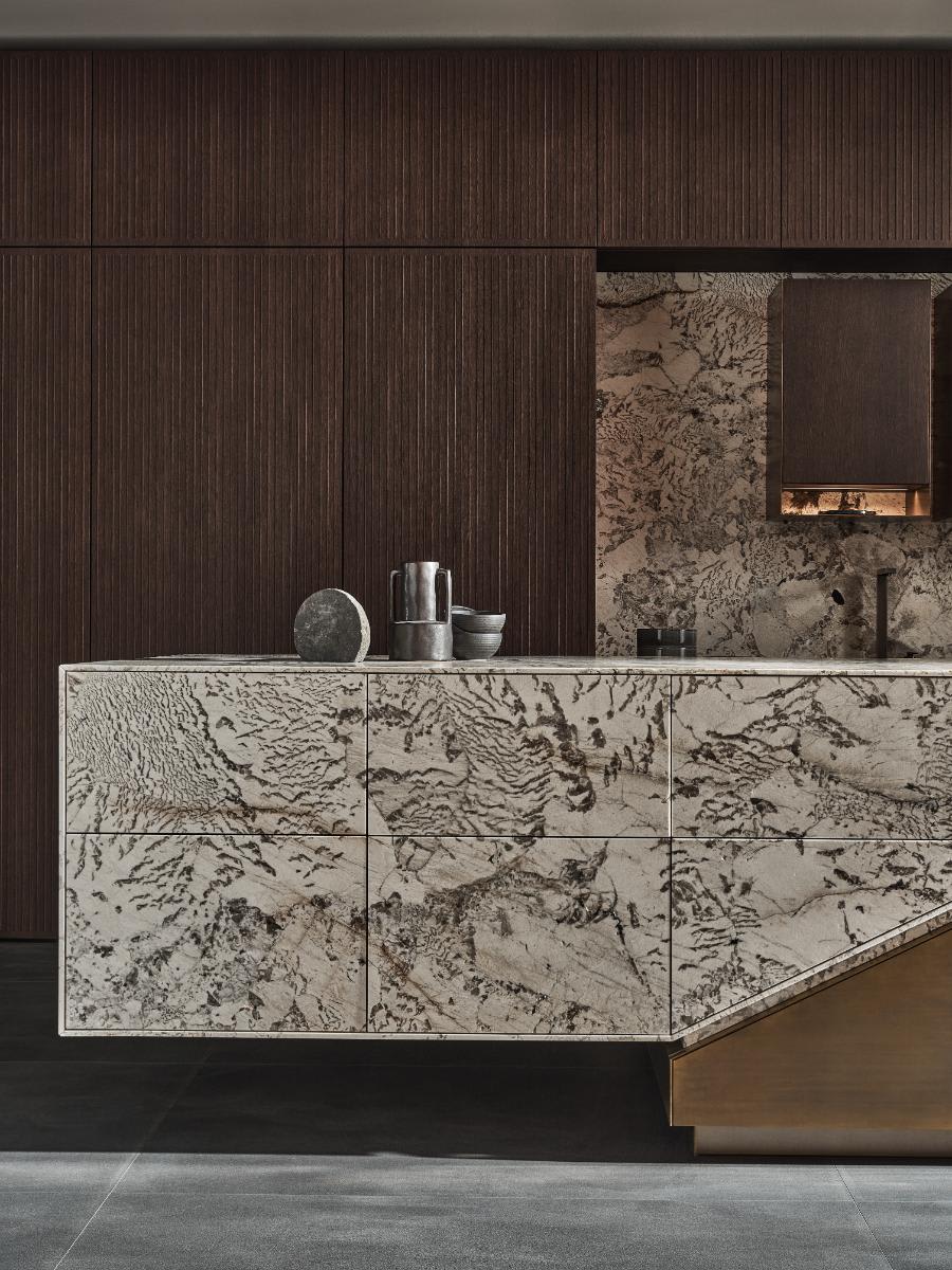 closeup of left marbleized end of the eggersmann skywalk kitchen island exhibit at eurocucina 2024 in salone del mobile in milan kitchen-island with wall cabinetry in lausanne 3561 Oak grey brown bicolor, brushed finish