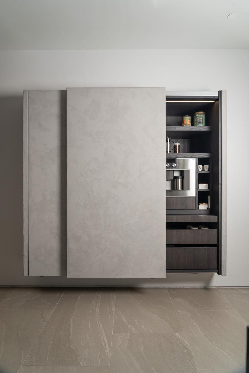 coplanar doors partially open on the right side revealing a coffee bar in a display kitchen in the eggersmann laguna showroom