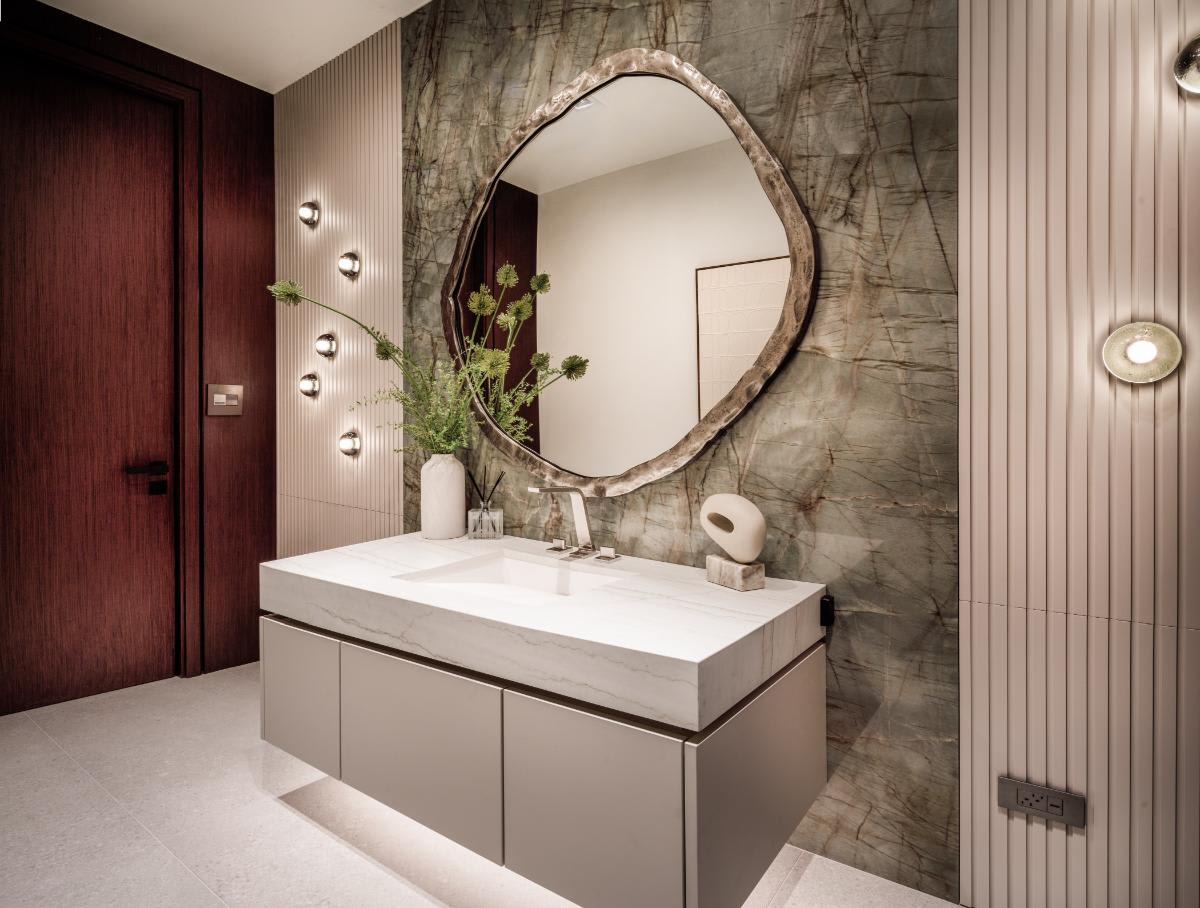 luxury bath display featuring an ultra-modern vanity and wall cabinetry in locarno vertically-grooved tambour style finish in the eggersmann houston showroom Sleek modern luxury bathroom vanity with marble countertop, minimalist cabinetry, wall cabinetry in locarno vertically-grooved tambour style finish, stylish mirror, and contemporary decorative elements, showcasing high-end German cabinetry craftsmanship.