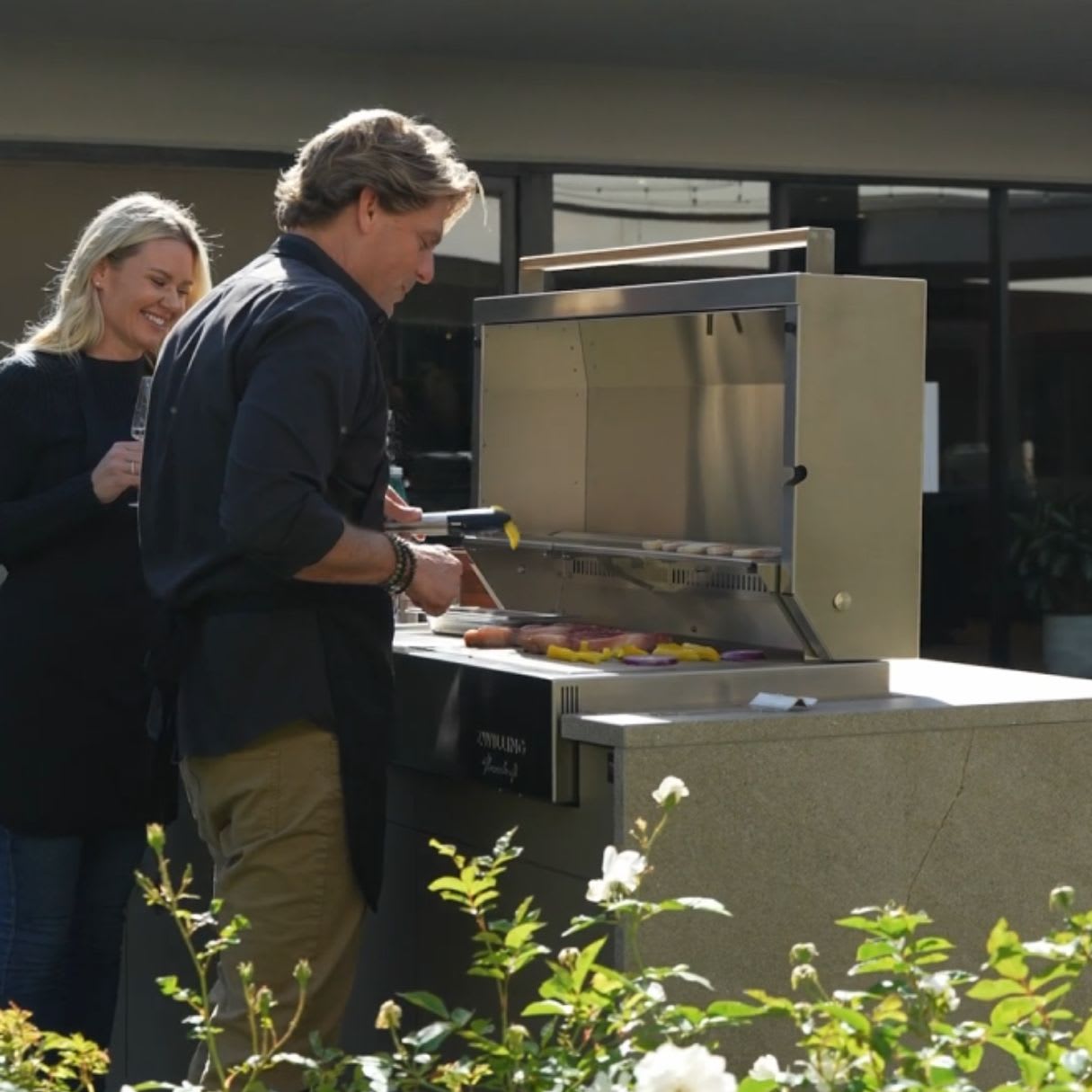 a couple grilling a healthy meal in the outdoor kitchen of the eggersmann laguna showroom