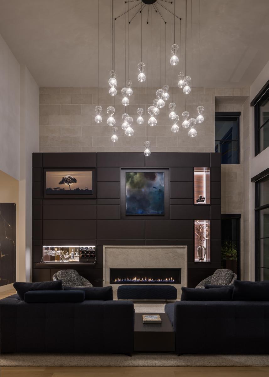 flip-down bar open and lit chandelier in a eggersmann-designed media wall of a luxury home living room in a home in leawood kansas
