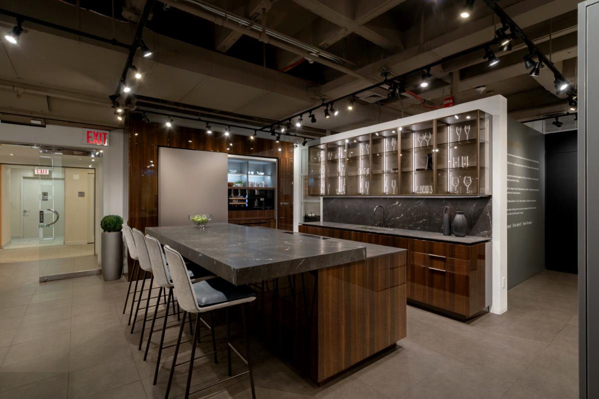 motion countertop extended with barstools with glance glass front upper cabinets and coplanar door unit right side open in a eggersmann nyc showroom display kitchen