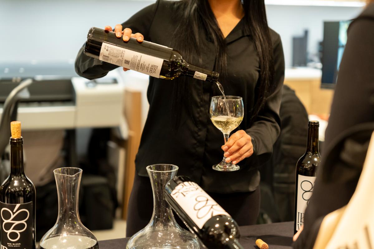 sommelier pouring wine for a guest at design west hollywood 2025 in the eggersmann la showroom