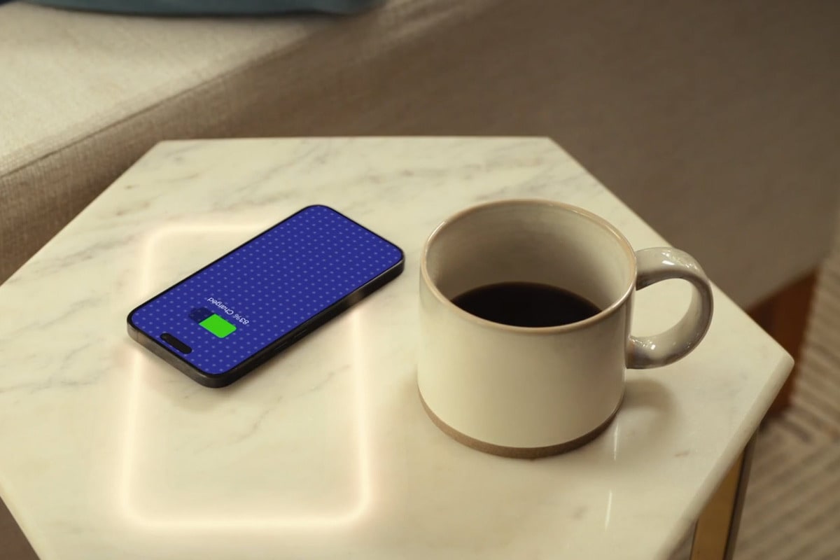 a cup of coffee and a phone wirelessly charging on freepower charging halo invisible device charger in a custom marble-topped end table