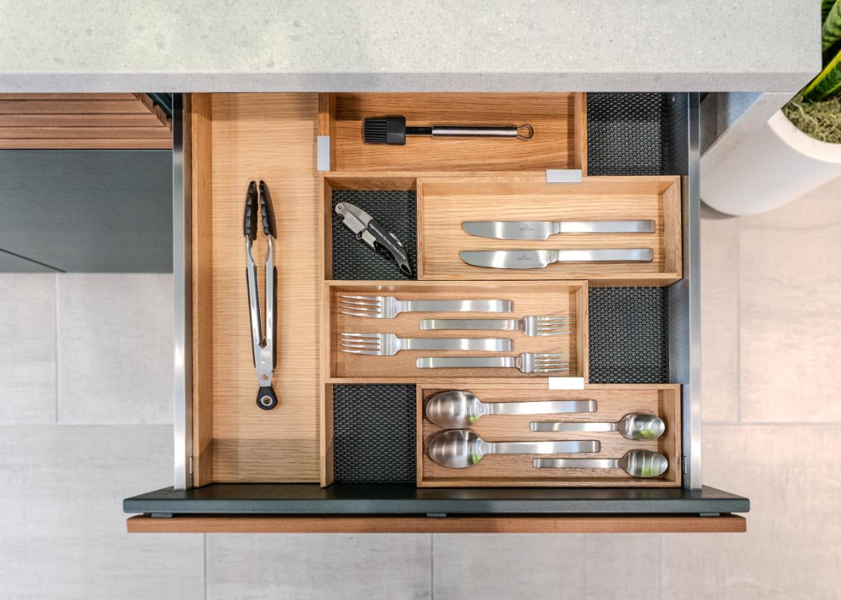 closeup of the wooden box organizers inside an open utensils drawer in the c4 kitchen island in the cubic outdoor kitchen display inside eggersmann la showroom