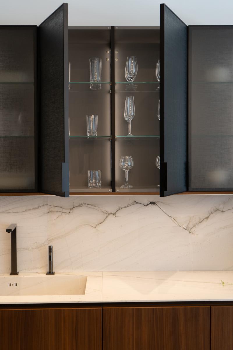 closeup of open cabinets in the smoked glass glance upper cabinets in the skywalk kitchen in the eggersmann la showroom