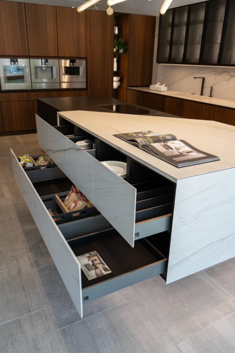 drawers open in the stone section of the skywalk kitchen island from the unique cabinetry collection in the eggersmann la showroom