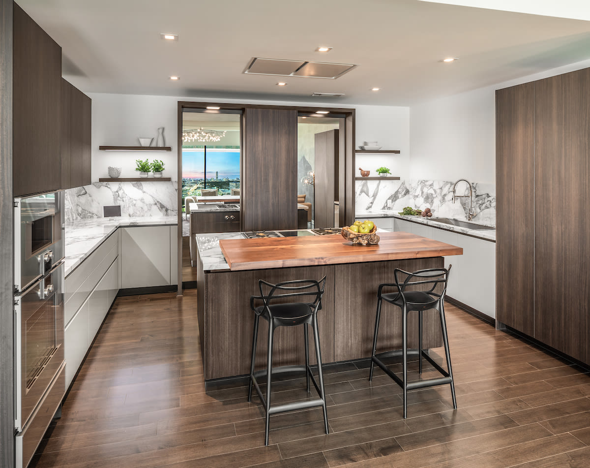 island with bar seating in a modern eggersmann usa kitchen design featuring work's turnstile organizational system and lighted open shelving.