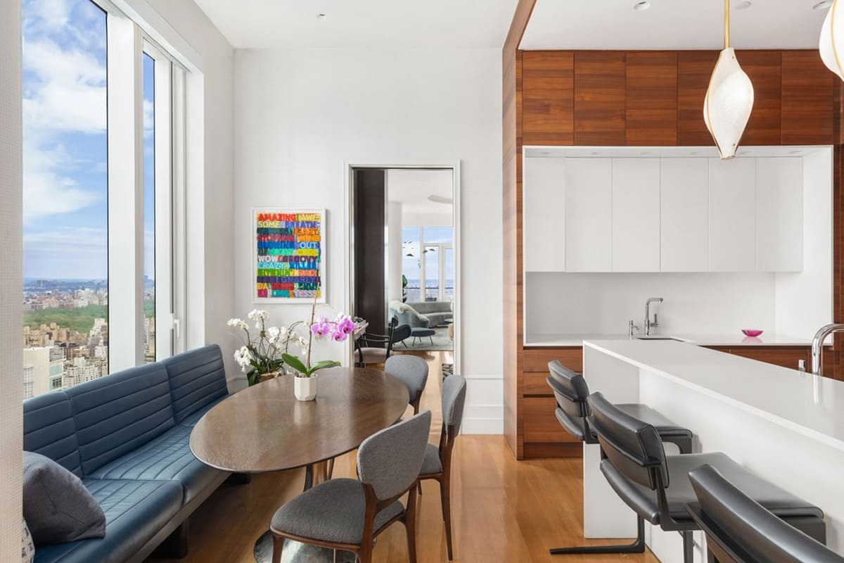 dining area with blue leather upholstered dining banquette next to a gloss white and wood-veneered kitchen and designed by eggersmann residence in 252 east 57th st of nyc