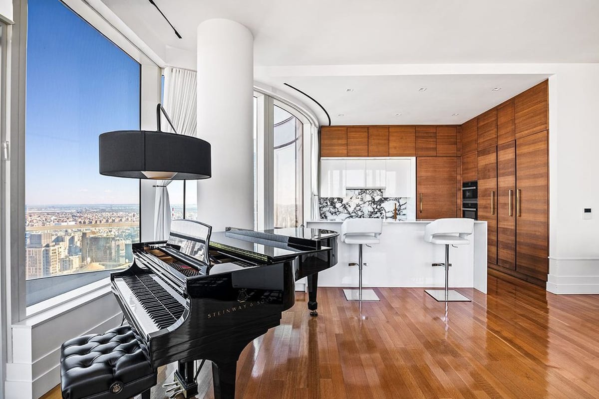 grand piano and white gloss kitchen island with horizontal wood veneer wall cabinetry designed by eggersmann residence in 252 east 57th st of nyc