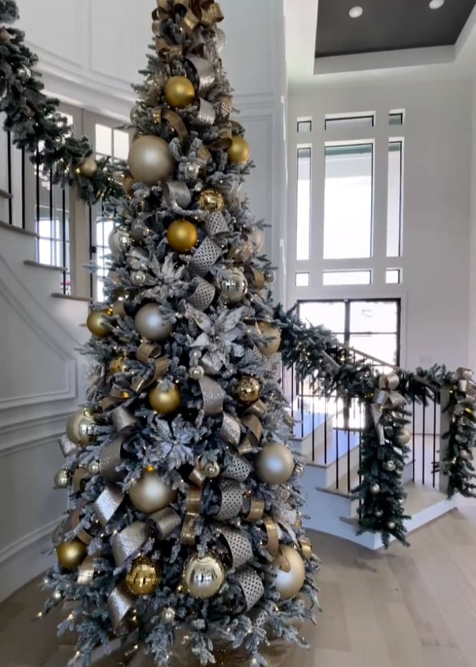 luxury christmas tree in front of a garland-draped staircase
