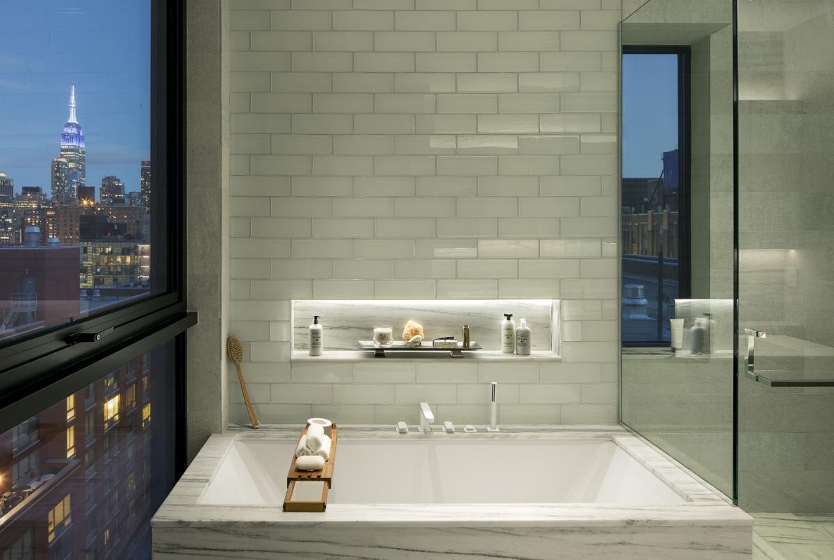 picture taken at night showing nyc out the windows and garden tub in a luxury bath designed by eggersmann in a residence of chelsea waterside nyc