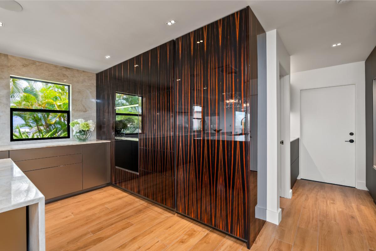 floor-to-ceiling-wall cabinetry in an exotic wood veneer, macassar amaro, in a glossy finish in a luxury kitchen designed by eggersmann laguna for a home in honolulu hawaii