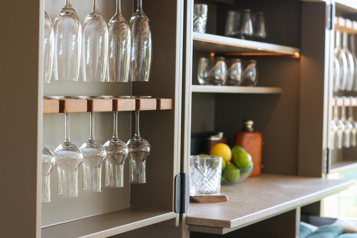 closeup of wine glass racks in a cubic kitchen in a cupboard with a light taupe interior and integrated refrigerator and sink