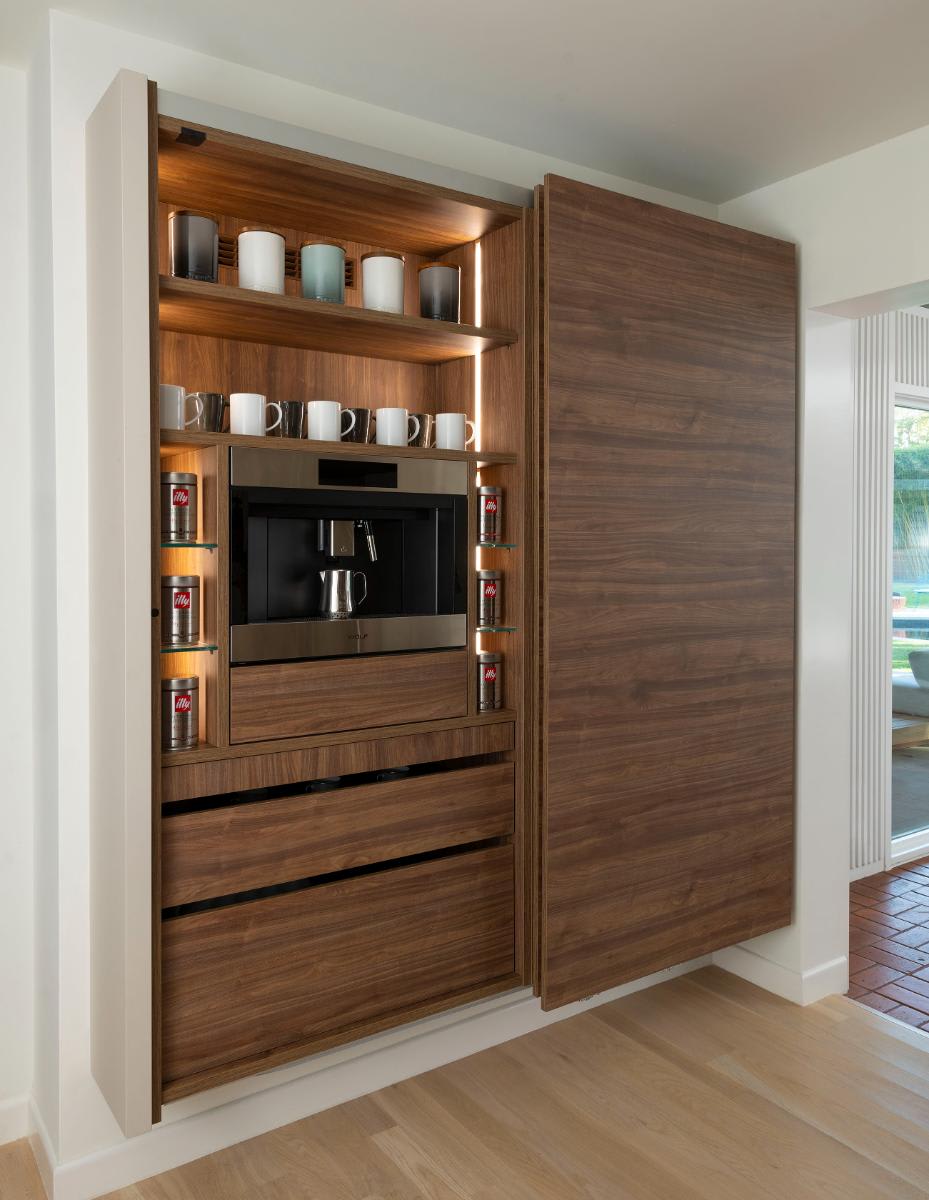 left coplanar door open in a horizontally grained wood veneer wall-mounted cabinet to reveal a coffee bar designed by eggersmann for a Preston Hollow kitchen renovation