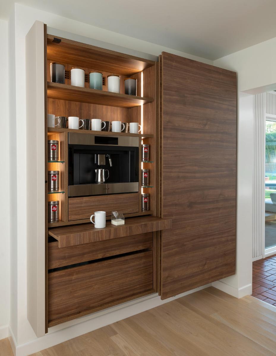 left coplanar door and pull-out counter open in a horizontally grained wood veneer wall-mounted cabinet to reveal a coffee bar designed by eggersmann for a Preston Hollow kitchen renovation